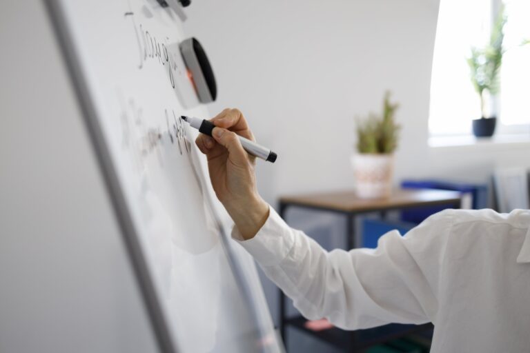 Woman hand with marker writing on white magnetic