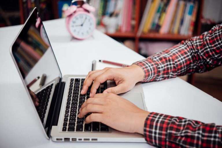Student taking notes on a laptop during a virtual class